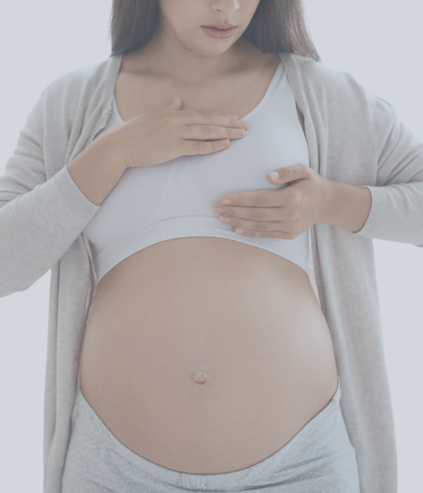 Schwangere Frau langt an ihre Brust.